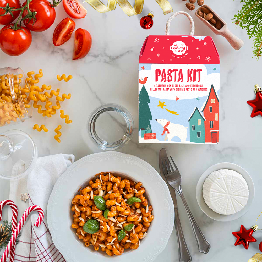 Tavolo in marmo con piatto di pasta con pesto siciliano e la Box graficata a tema natalizio