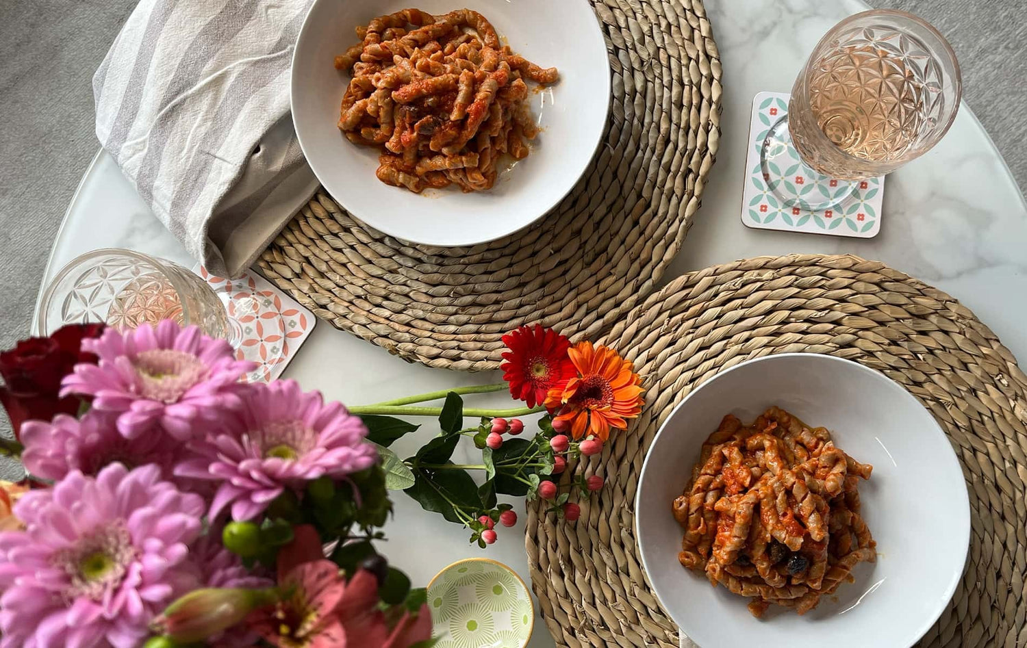 Piatto di busiate siciliane con centro tavola di fiori primaverili